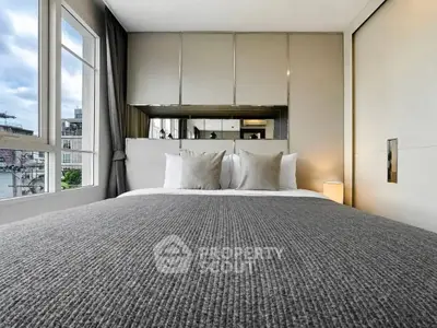 Luxurious bedroom with large windows and elegant decor in modern apartment.