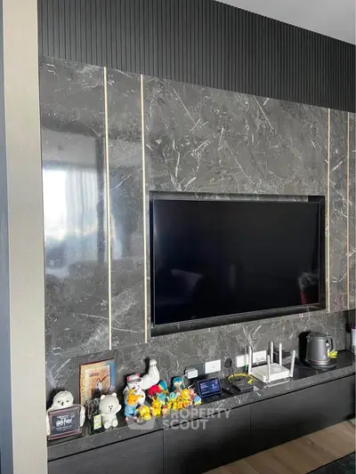 Modern living room with sleek marble wall and mounted TV, featuring stylish decor and entertainment setup.