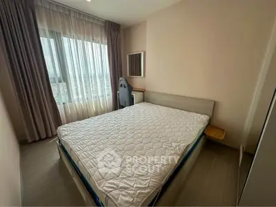 Spacious bedroom with large window and modern furnishings in a high-rise apartment.
