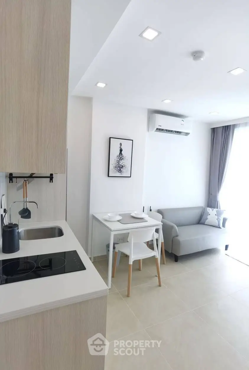Modern open-layout living room with kitchen, featuring sleek design and natural light.