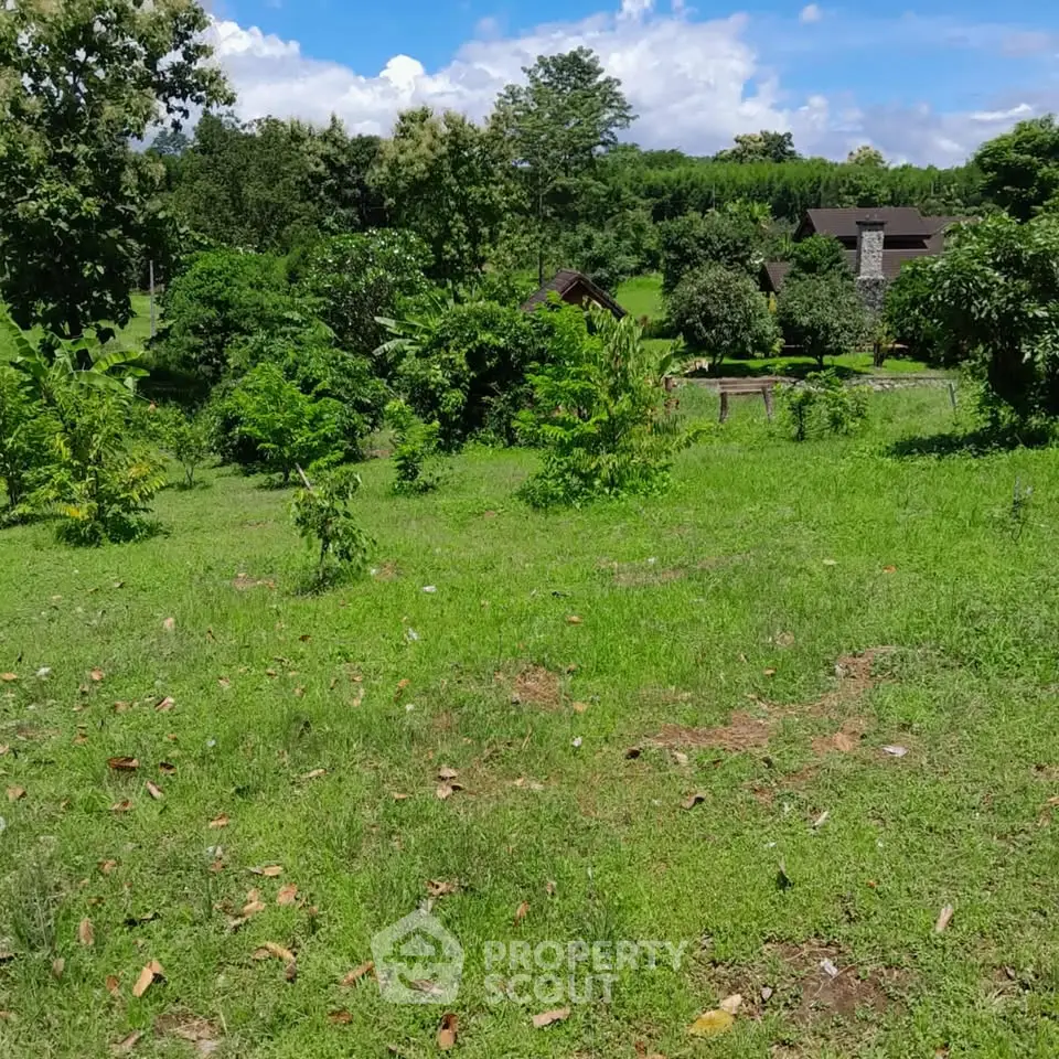 Scenic view of lush green land with distant houses, perfect for real estate development.