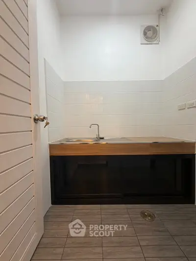 Modern kitchen with sleek wooden countertop and tiled backsplash in a compact layout.