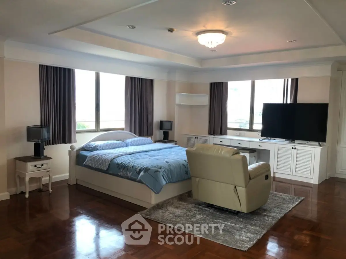 Spacious bedroom with elegant decor and large windows offering natural light.