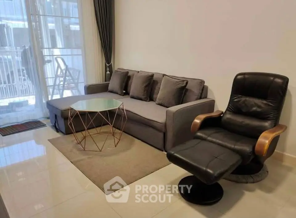 Modern living room with stylish sofa and armchair, featuring a chic glass coffee table and elegant decor.