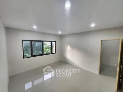 Spacious empty room with large window and glossy tiled floor, perfect for customization.