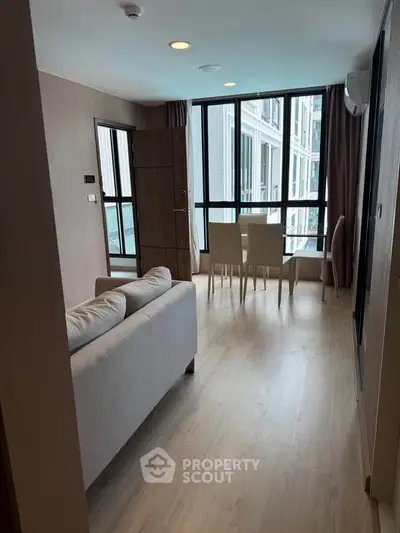 Modern living room with floor-to-ceiling windows and dining area in a stylish apartment.