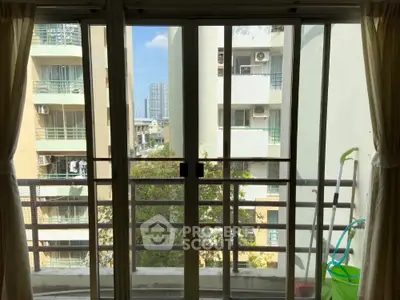 City view from apartment balcony with sliding glass doors and curtains