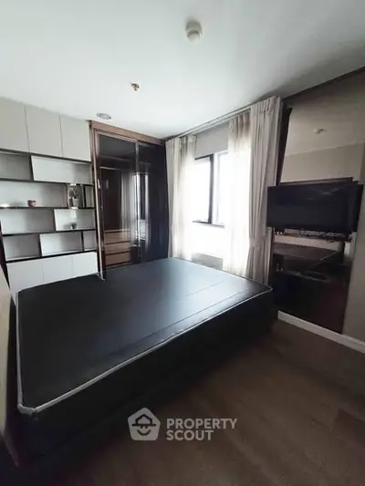Modern bedroom with sleek design and ample natural light, featuring a large bed and built-in storage.