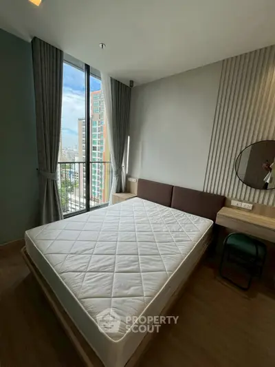 Modern bedroom with large window and city view, featuring a comfortable bed and stylish decor.