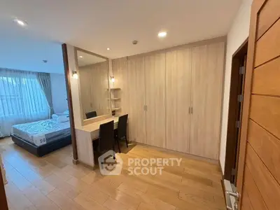 Spacious bedroom with wooden flooring, large wardrobe, and cozy bed, perfect for relaxation.