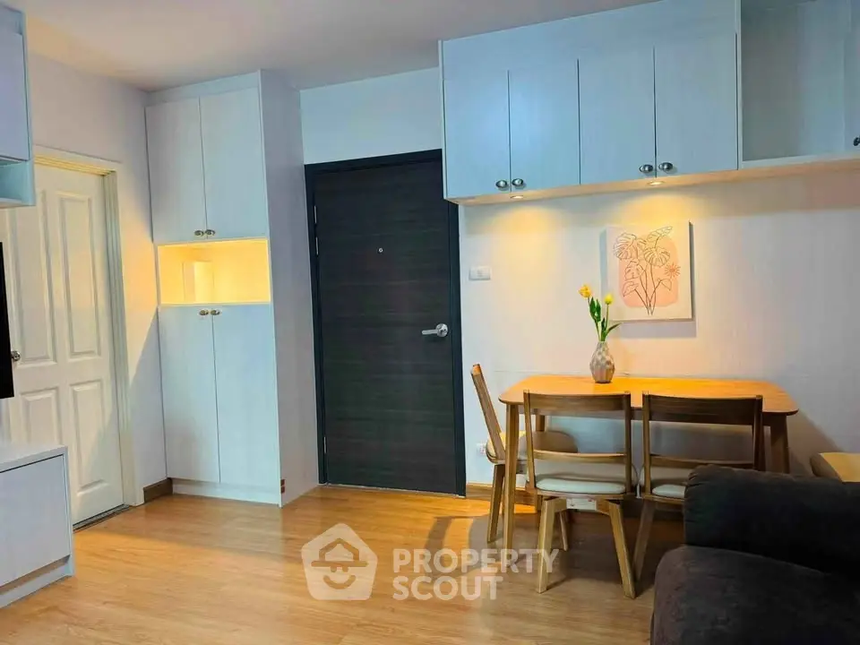 Cozy living room with wooden flooring, dining table, and modern cabinetry in a stylish apartment.