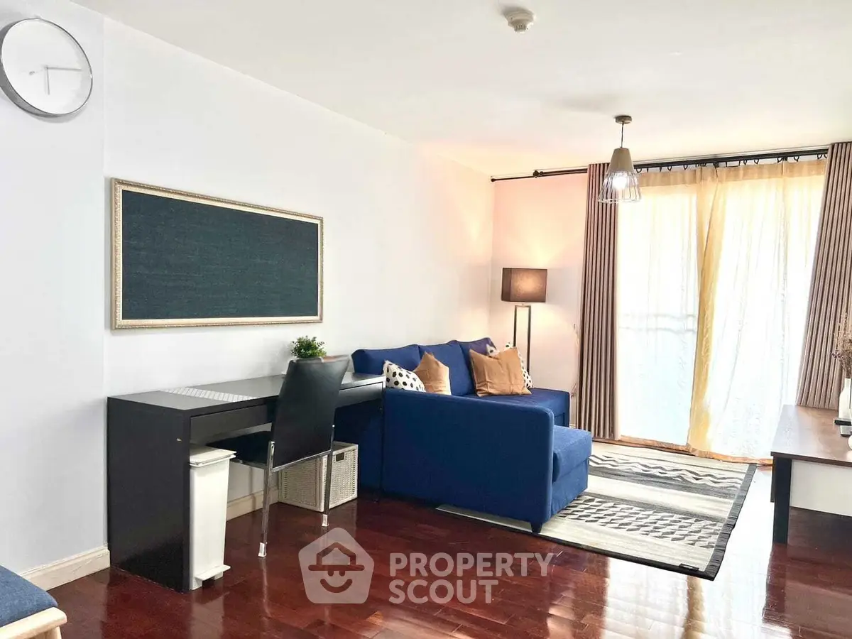 Modern living room with blue sofa, stylish decor, and natural light from large windows.