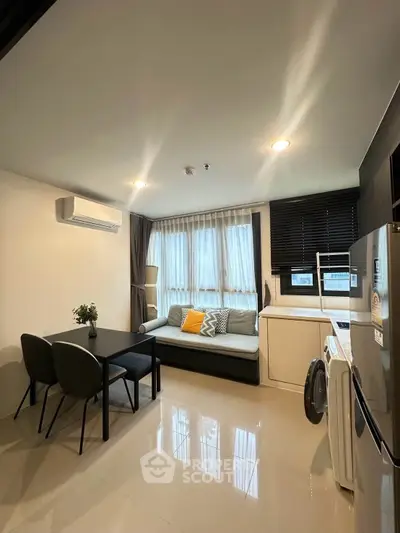 Modern living room with sleek furniture and natural light, featuring a compact kitchen and stylish decor.