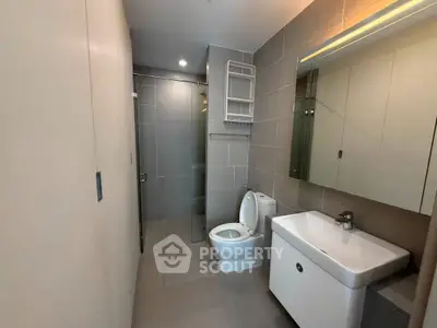Modern bathroom with sleek fixtures and spacious shower area in a contemporary apartment.