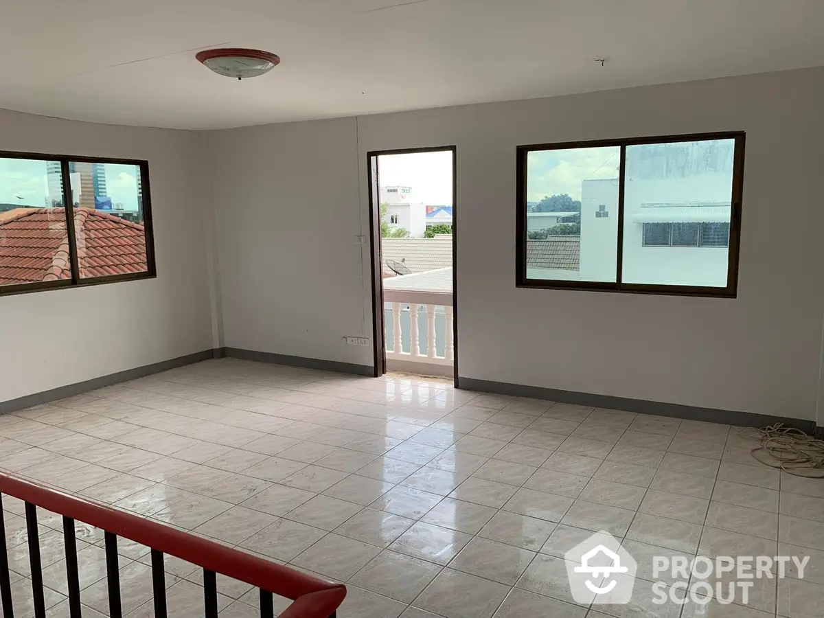 Spacious and sunlit living room with gleaming tiled floors, large windows offering ample natural light, and a charming balcony with a view, ideal for comfortable urban living.