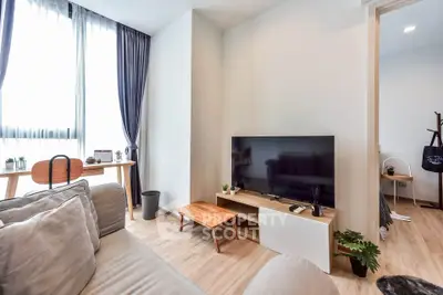 Modern living room with natural light, stylish furniture, and a sleek TV setup.