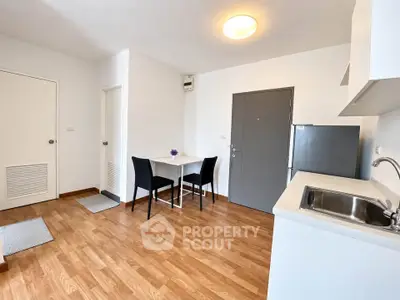 Modern kitchen with sleek design, wooden flooring, and compact dining area in a cozy apartment.