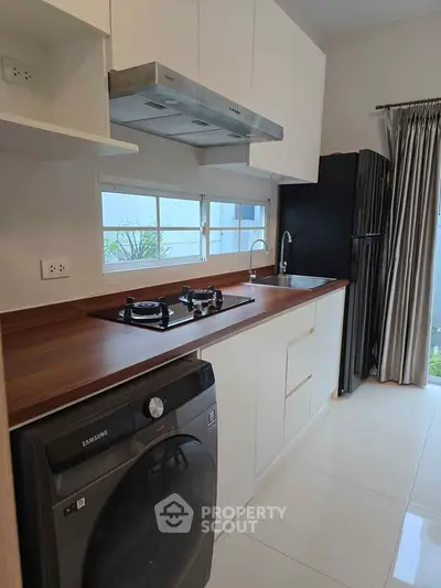 Modern kitchen with gas stove, washing machine, and sleek cabinetry