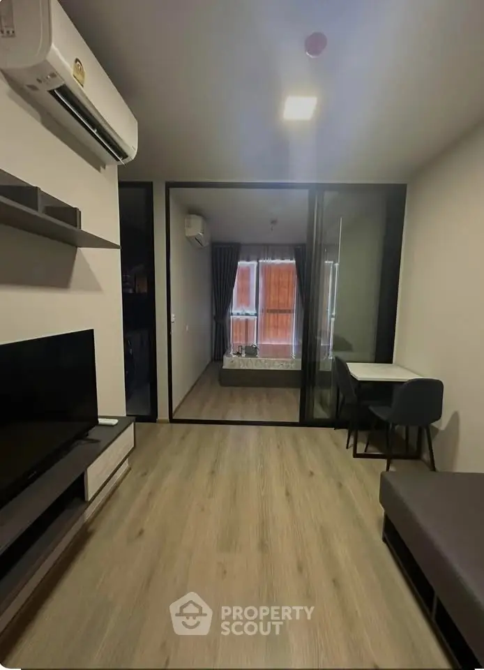 Modern living room with sleek design and glass partition leading to bedroom