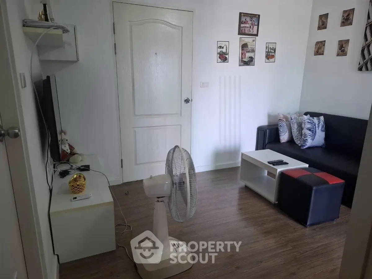 Cozy living room with modern decor and wooden flooring, featuring a comfortable sofa and entertainment setup.