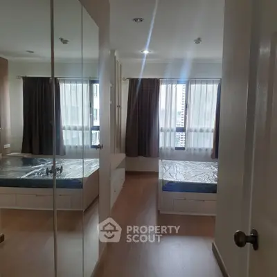 Spacious bedroom with large windows and mirrored closet doors in modern apartment