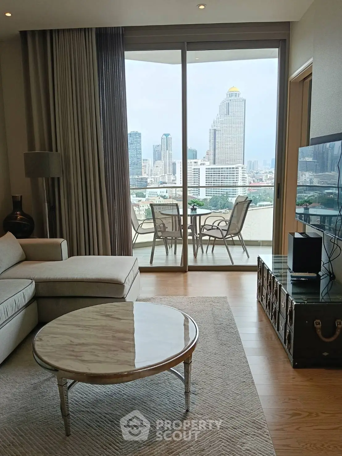 Luxurious living room with stunning city view from large balcony, featuring elegant furniture and modern decor.