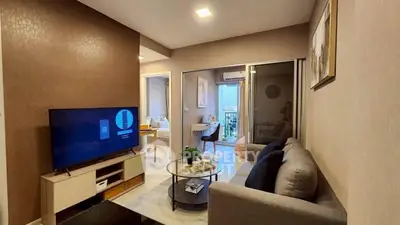 Modern living room with cozy sofa and TV, leading to a bright balcony view.