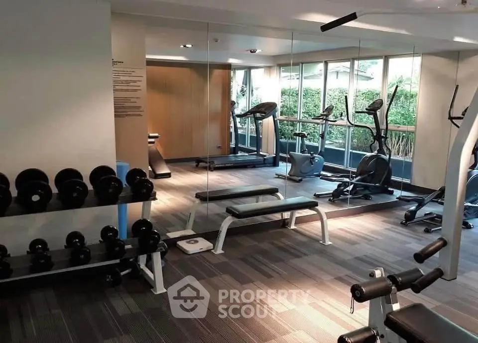 Modern gym with exercise equipment and large windows in a residential building.