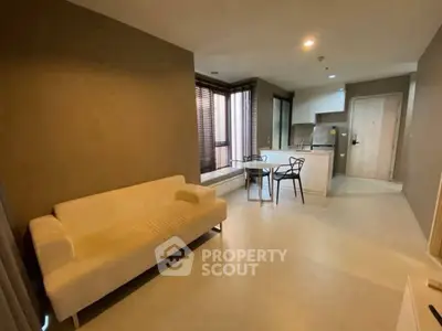 Modern open-layout living room with cozy sofa and stylish kitchen area.