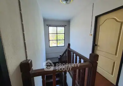 Charming stairway with wooden railing and bright window view