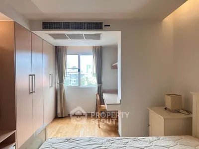 Bright bedroom with large window, built-in wardrobe, and study desk, offering a cozy and functional living space.