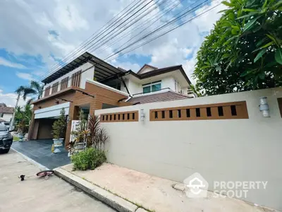 Spacious two-story residence with modern design, featuring a covered carport, elegant wood accents, and lush greenery enhancing curb appeal.