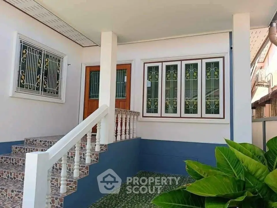 Charming home entrance with decorative windows and lush greenery