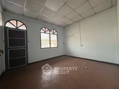Spacious empty room with parquet flooring and arched windows, ideal for customization.