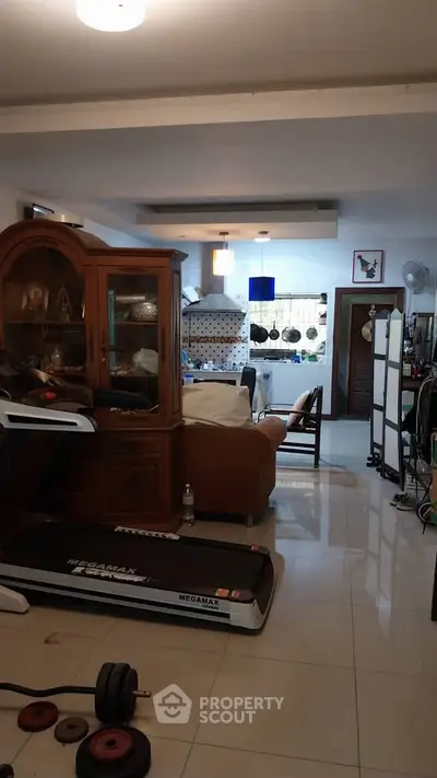 Spacious living room with treadmill and open kitchen layout, perfect for modern living.