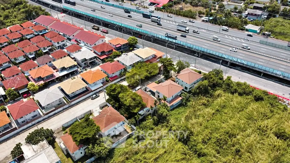 Aerial view of suburban houses near a highway, showcasing a vibrant residential area with easy access to main roads.