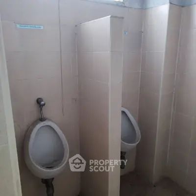 Public restroom with two urinals and tiled walls, suitable for commercial properties.