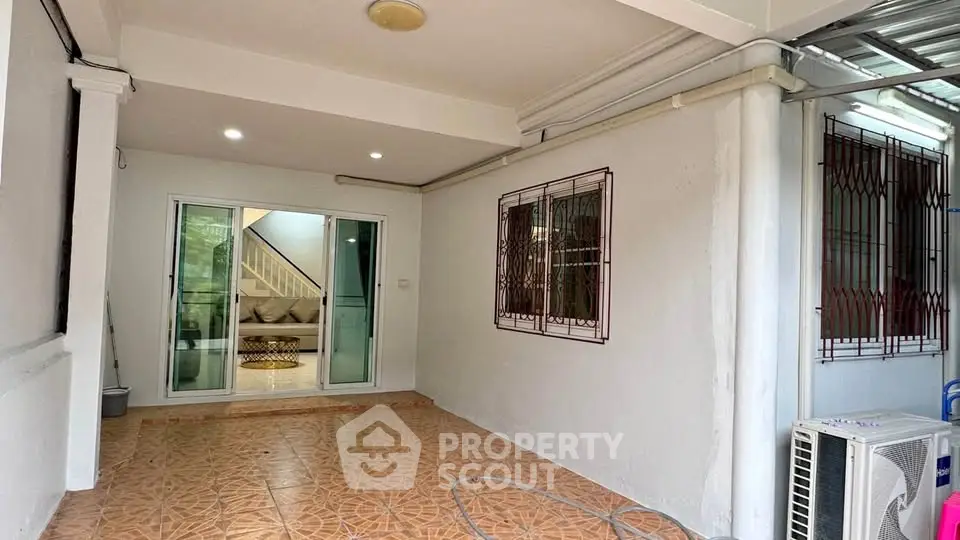 Spacious covered patio with sliding glass doors and tiled flooring