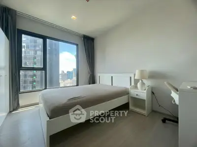 Modern bedroom with city view, featuring sleek furniture and large window for natural light.