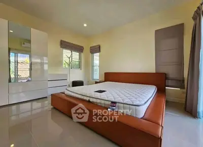 Spacious bedroom with modern furniture and large windows for natural light.