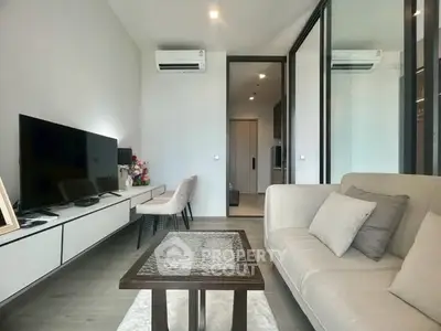 Modern living room with sleek furniture and large TV, featuring air conditioning and elegant decor.
