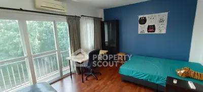 Cozy bedroom with balcony view, wooden flooring, and stylish blue accent wall.