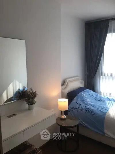 Cozy bedroom with elegant decor and natural light, featuring a stylish bed and a chic lamp.