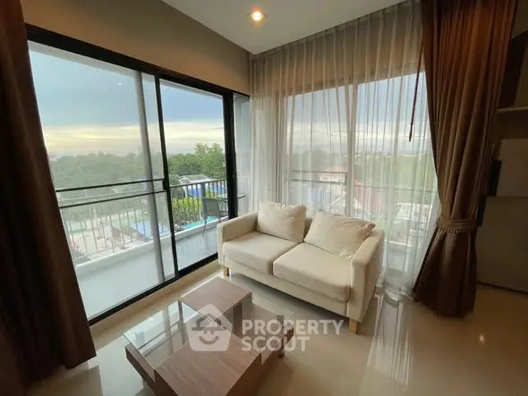 Modern living room with large windows and balcony view, featuring a cozy sofa and elegant curtains.
