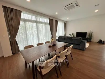 Spacious and modern open-plan living area with large dining table, comfortable seating, and ample natural light from floor-to-ceiling windows, perfect for entertaining.