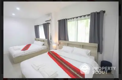 Spacious bedroom with two beds and modern decor, perfect for comfortable living.