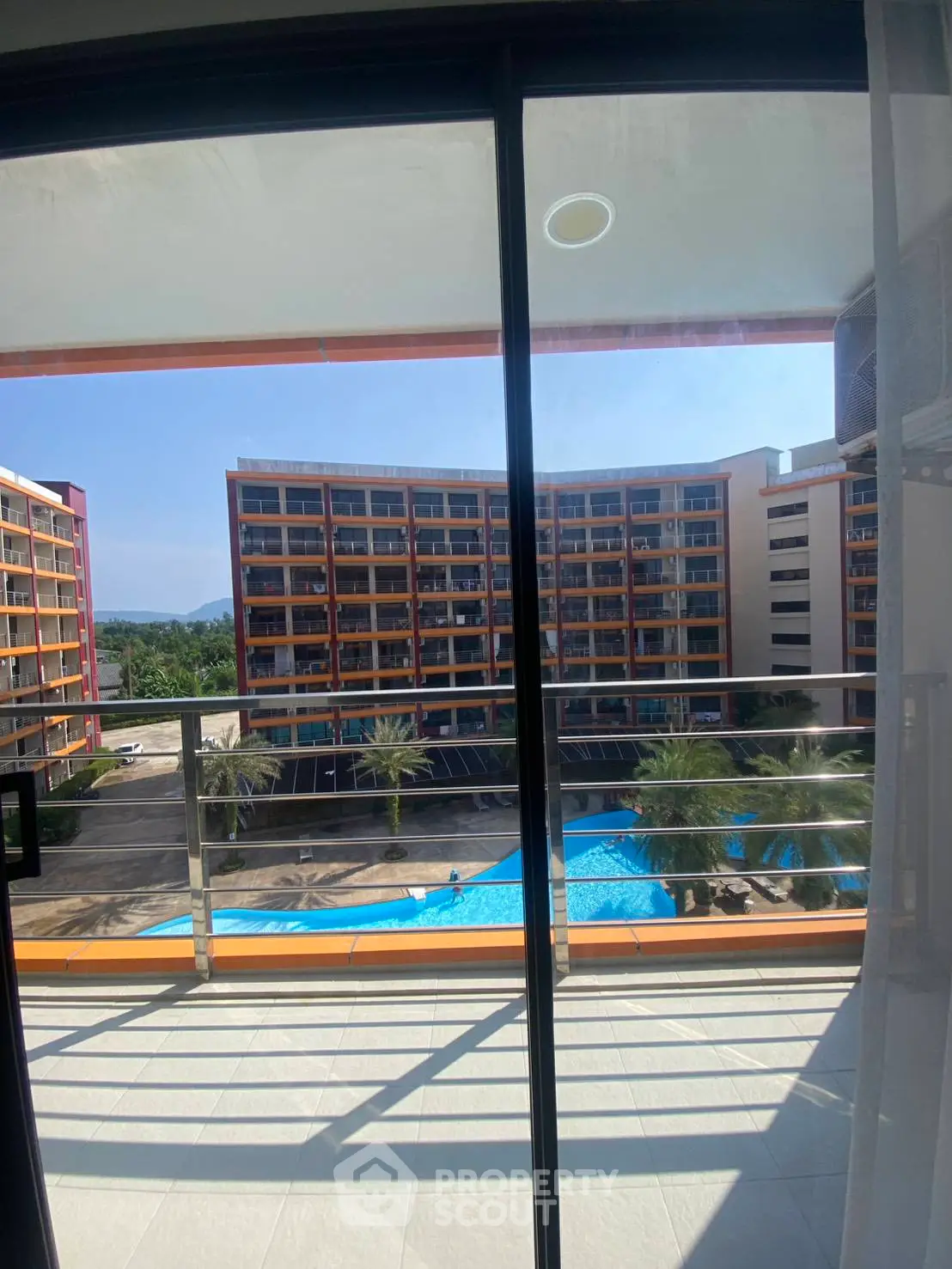 Stunning balcony view of modern apartment complex with pool and lush surroundings.