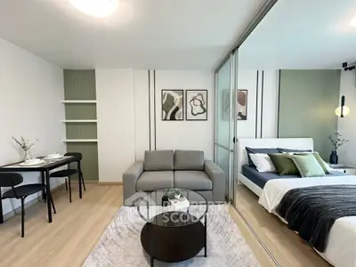 Modern open-plan living room with stylish decor and cozy bedroom area, perfect for urban living.