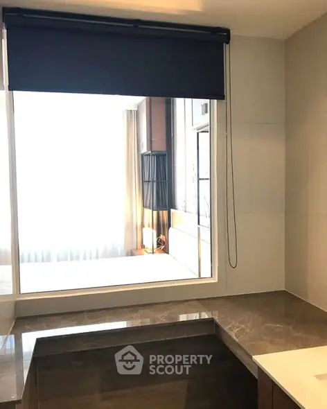 Modern bathroom with marble countertop and large window overlooking bedroom