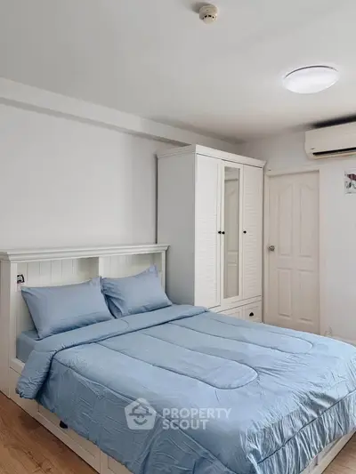 Cozy bedroom with blue bedding, white wardrobe, and air conditioning in modern apartment.